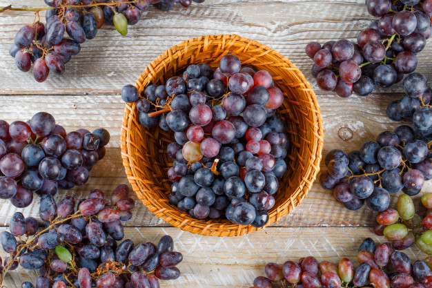 ripe-grapes-wicker-basket-wooden-background-flat-lay_176474-9812