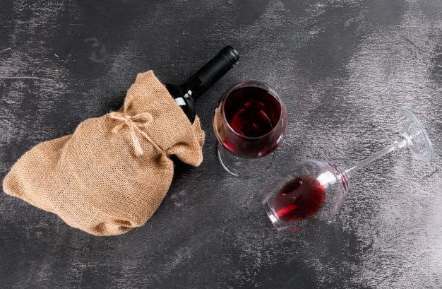side-view-red-wine-bottle-sackcloth-bag-black-stone-horizontal_176474-4121